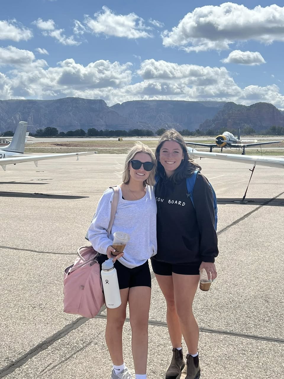Two people on the airfield ramp with aircraft behind them