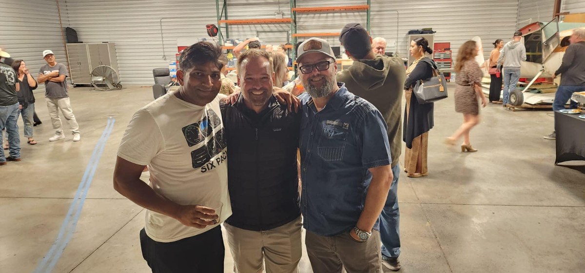 Three pilots posing together at a hangar event