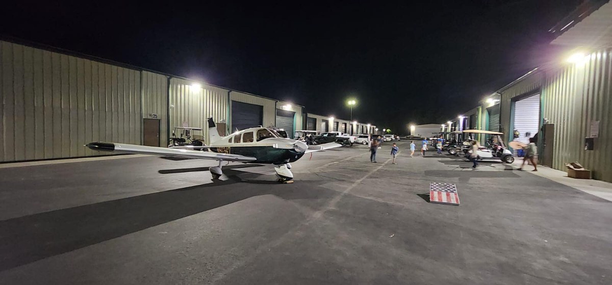 Aircraft parked on the ramp at night with hangar lighting