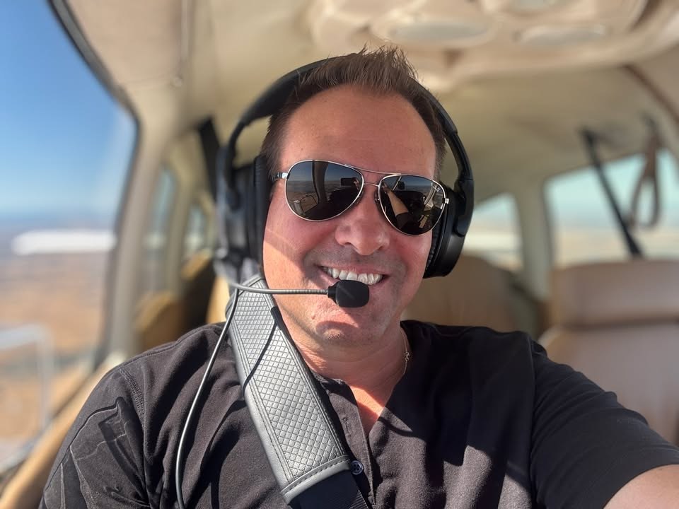 Pilot in cockpit wearing aviator sunglasses and aviation headset