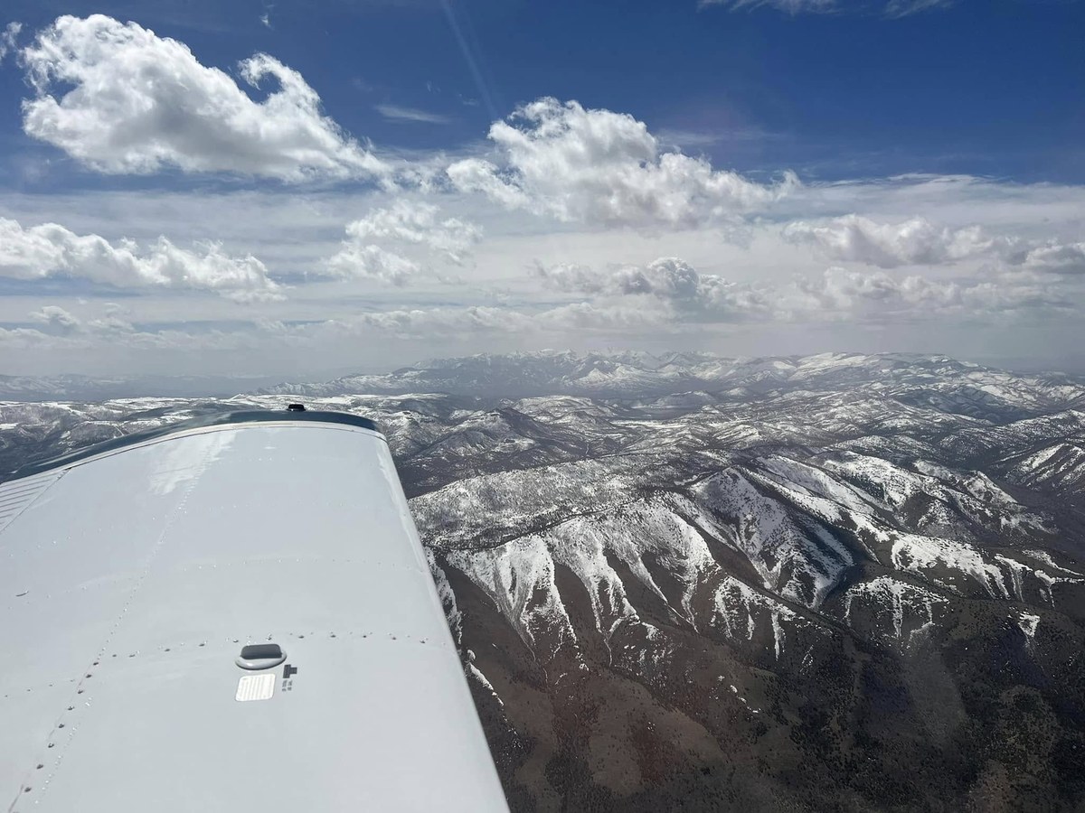 Aerial view of snow-capped mountains with aircraft wing visible