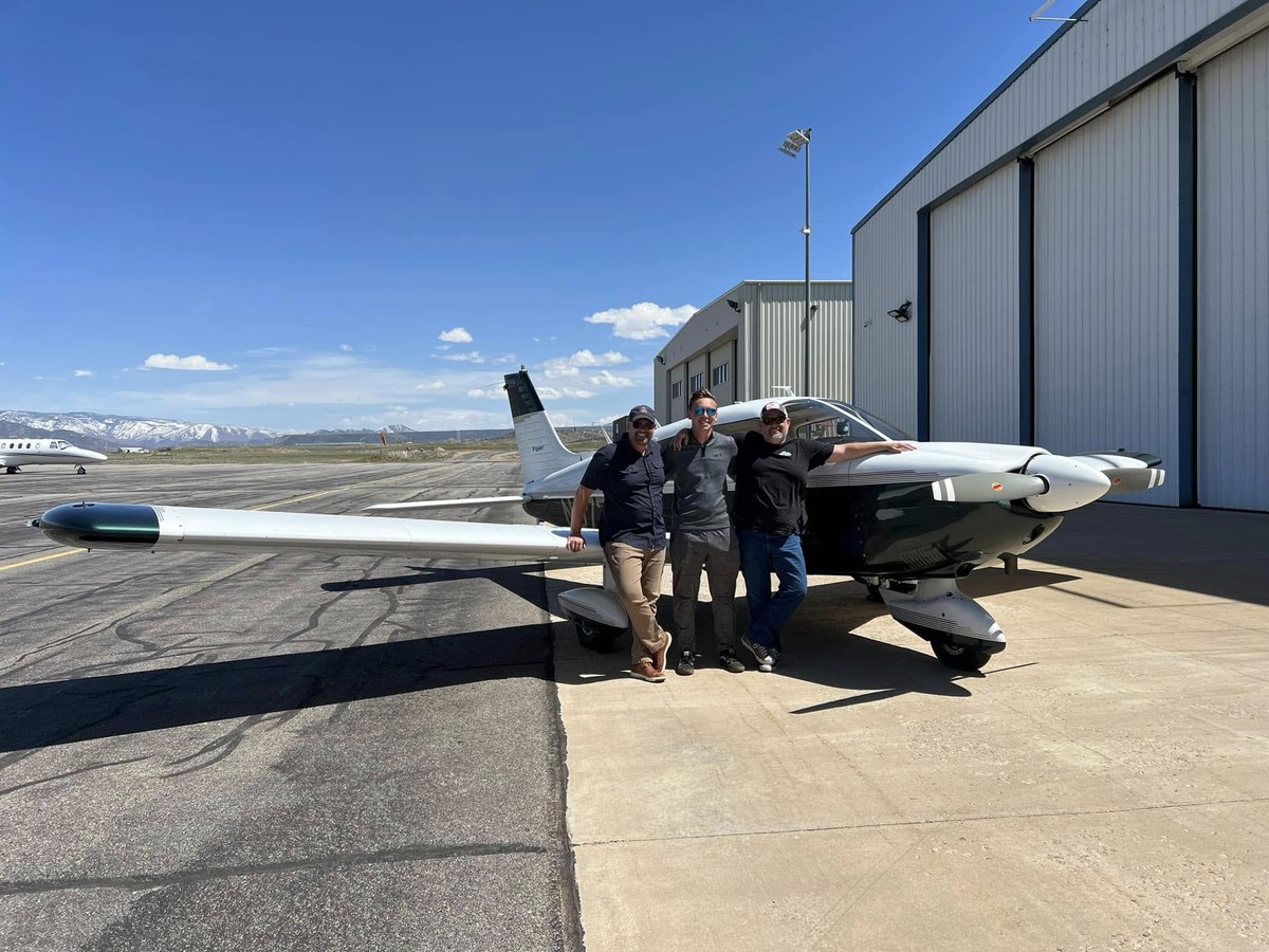 Pilots and passengers standing next to a Cessna on the tarmac
